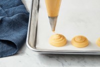 Pâte à choux being piped on baking sheet