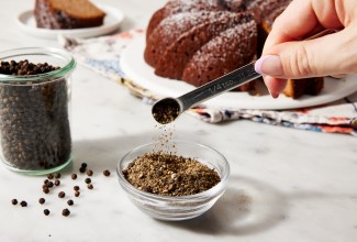 Small glass bowl of ground pepper in front of a Bundt cake