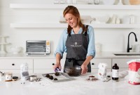 A baker scooping cookies in the kitchen with a Breville Smart Oven in the background