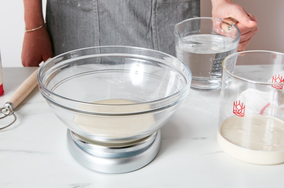 Bowl of sourdough starter on scale next to a crock with sourdough starter