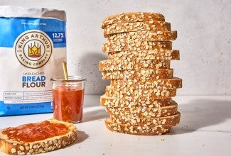 Bag of bread flour behind a sliced loaf of oatmeal sandwich bread